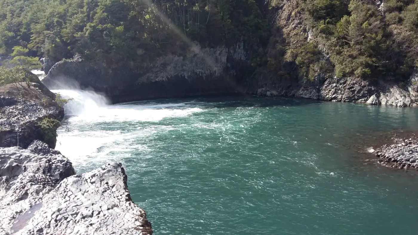Río turquesa entre rocas con una pequeña cascada
